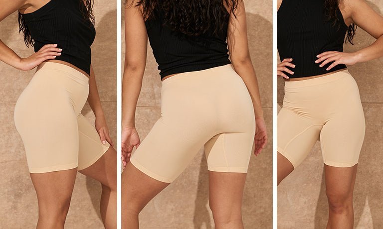 Front, back, and side views of nude chafewear shorts showing seamless, form-fitting mid-thigh fit on model against beige wall