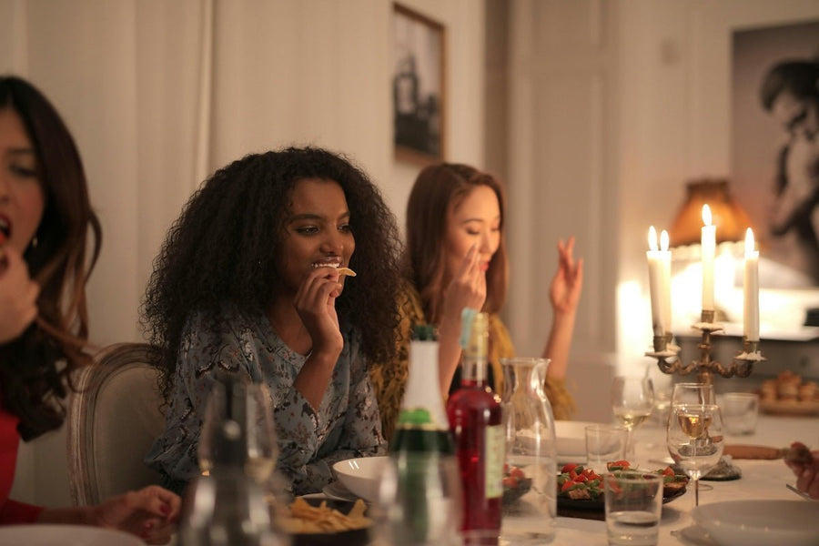 Three people enjoying a cozy candlelit dinner at a warmly lit dining table