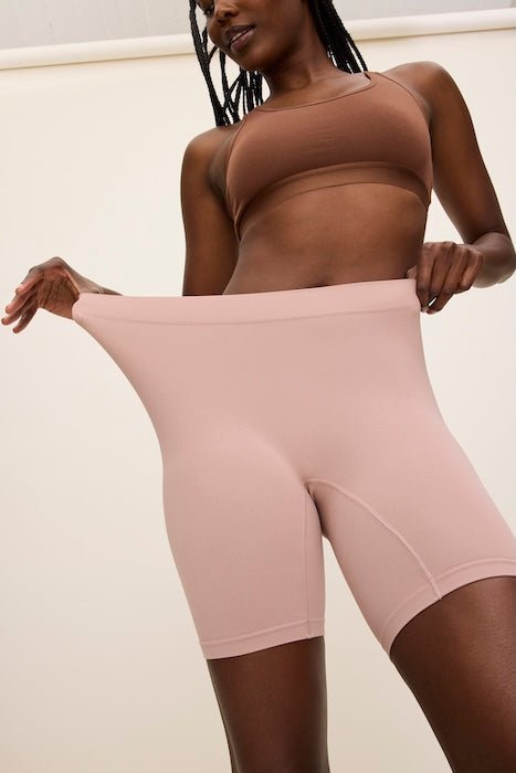 Low-angle front view of sandstone high-waist bike shorts showing a stretchy waistband and seamless fabric on a model