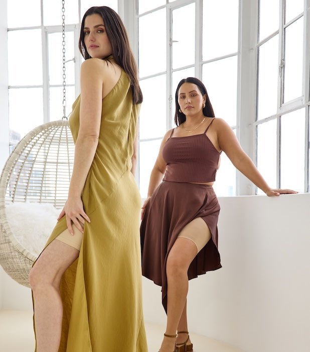 Two models wearing fall wedding looks: mustard side-slit maxi revealing beige thigh band; brown crop top and midi skirt