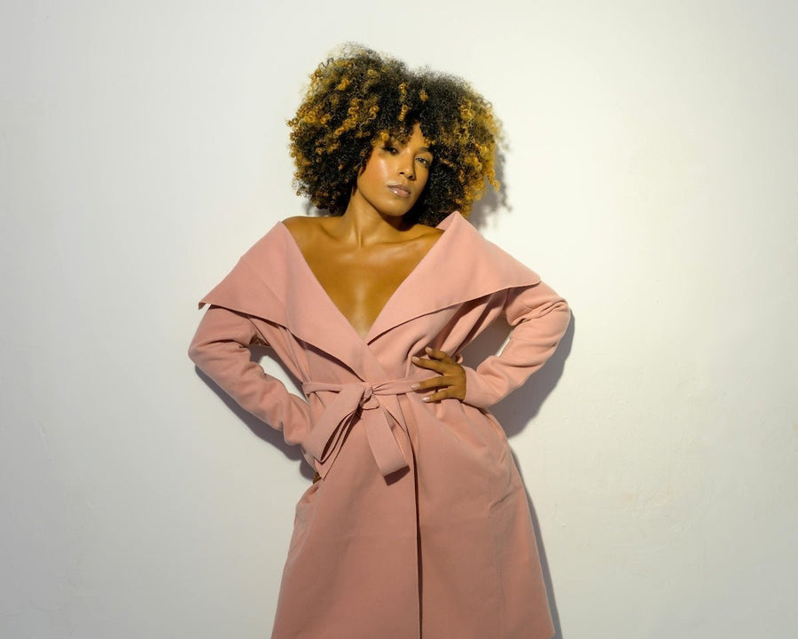Front view of model wearing a dusty pink wrap dress tied at the waist with an oversized off-shoulder collar against a plain white background