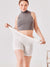 Front view of The Cooling 5-inch Halo shorts in white on model stretching the waistband to show high stretch, light background