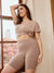 Three quarter view of Original 7 inch taupe anti-chafe shorts showcasing high-rise waistband and mid-thigh fit with window and flowering trees in background