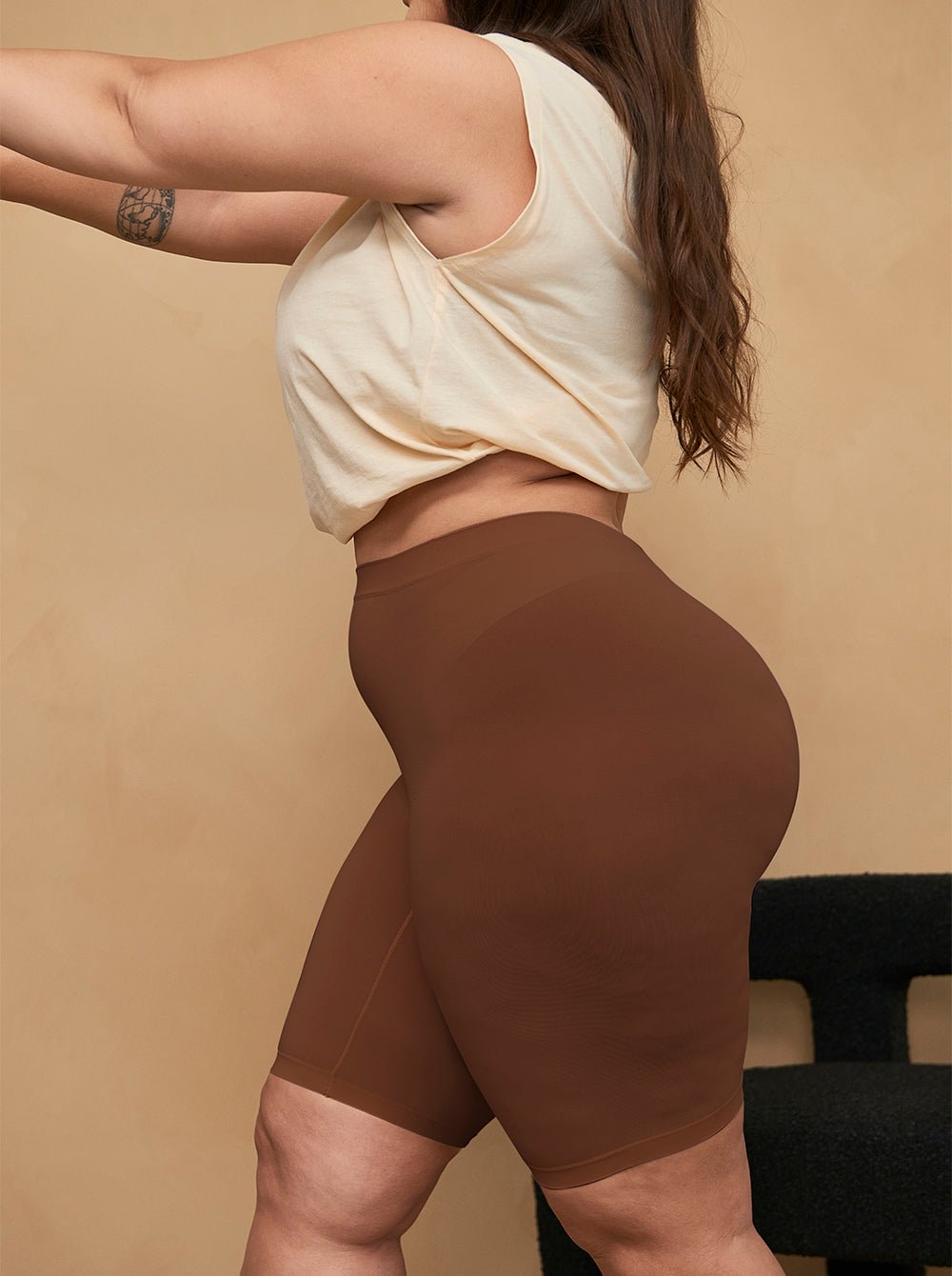Side view of Cooling 9-inch anti-chafe shorts in cocoa on model, high-rise fit showing thigh coverage and smooth fabric, beige background