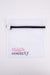 Top-down view of white mesh delicates wash bag with black zipper and pink and gray thigh society logo on white background